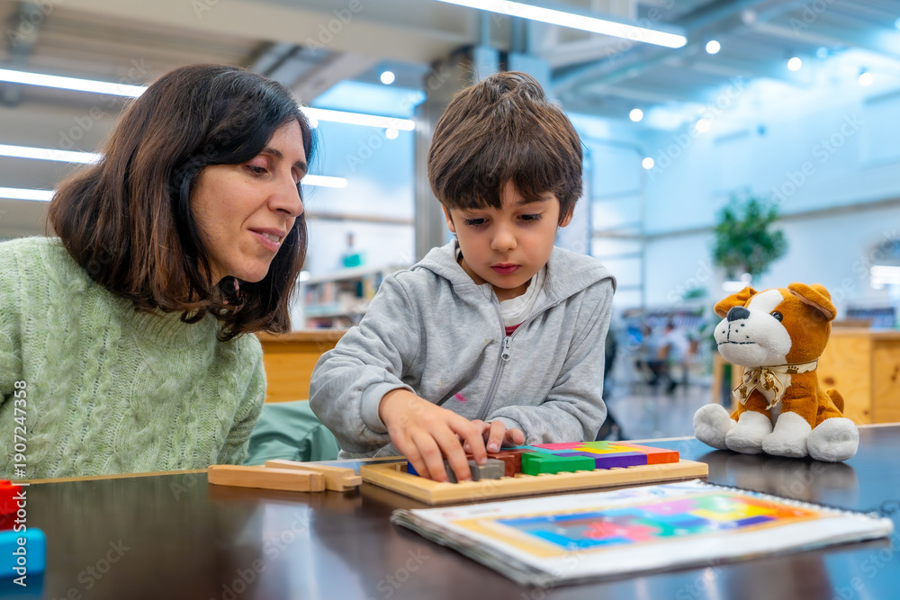 Obraz premium Teacher helping young boy playing learning game puzzle