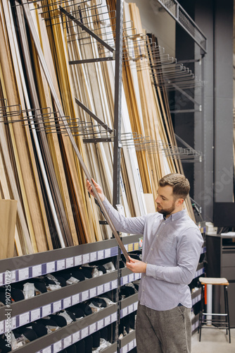 Tableau sur toile Man choosing decorative wooden moldings and trim for home improvement, shopping