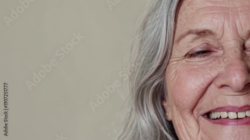 Detailed view of a happy elderly lady with silver hair smiling warmly while displaying natural facial aging lines