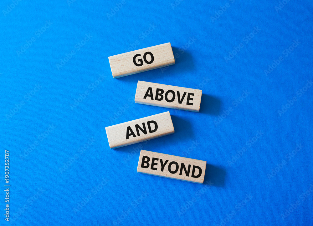 Obraz premium Go above and beyond symbol. Concept words Go above and beyond on wooden blocks. Beautiful bright blue background. Business and Go above and beyond concept. Copy space.