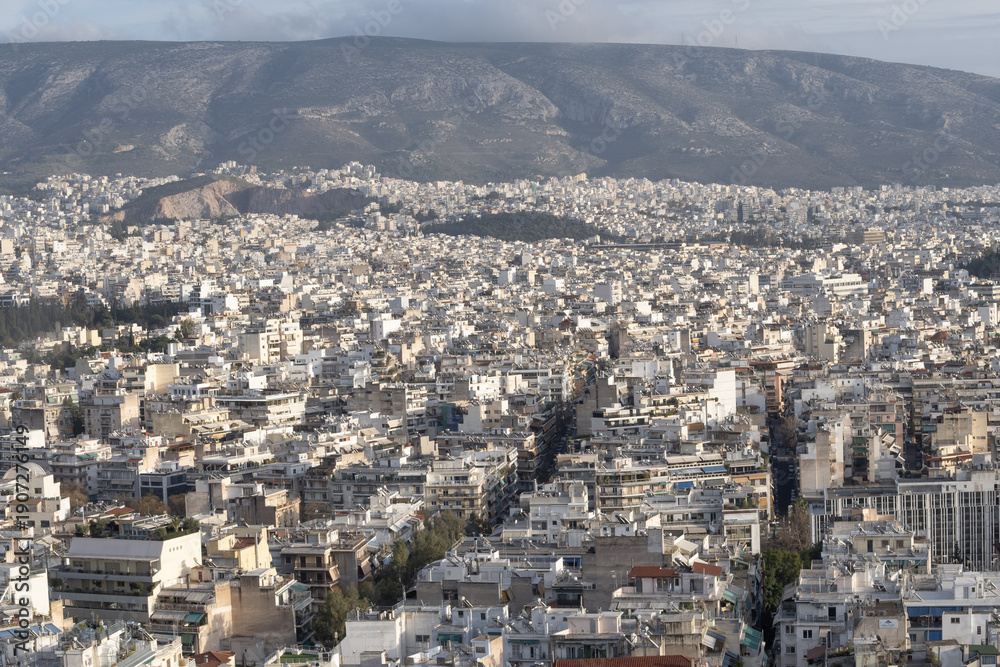 Fototapeta premium High angle view of Athens city from Filopappou Hill with compact white buildings, dense urban structure and mountain landscape in Greece.