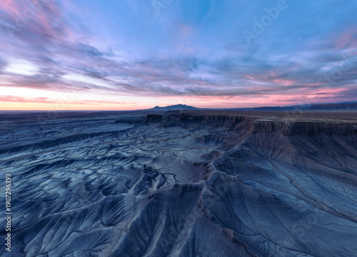 Aerial view of a surreal landscape where the rugged, textured earth meets the soft pastel hues of the dawn sky, Hanksville, Utah, United States.