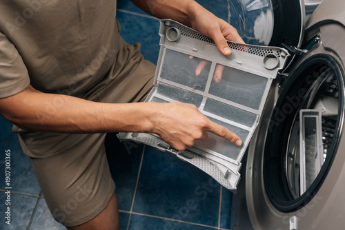 Cuadro en lienzo Person removing lint from tumble dryer filter, performing routine household chore and essential appliance maintenance, ensuring proper functioning and preventing fire hazards