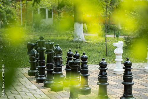 White and black giant chess pieces in a green spring city park. Biryuch, Belgorod region, Russia