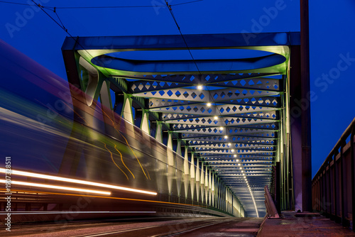 Photography historic iron tram bridge in Bratislava with a moving illuminated tram, against