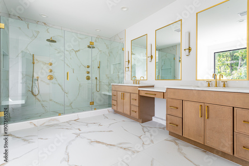 Luxury modern bathroom interior with double vanity, glass shower, marble tile and gold fixtures