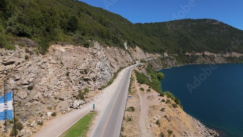 Aerial view of Lake Lacar and San Martin de los Andes in Patagonia, highlighting a scenic marina with numerous sailboats and boats anchored in deep blue water surrounded by mountains.
