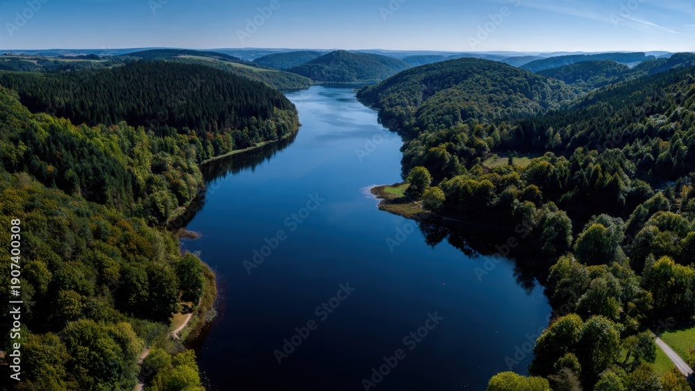 Fototapeta premium Reservoir surrounded by lush forest, aerial view