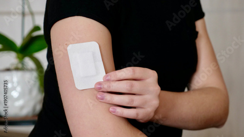 Fotografía female hand holding a white medical bandage patch on her shoulder