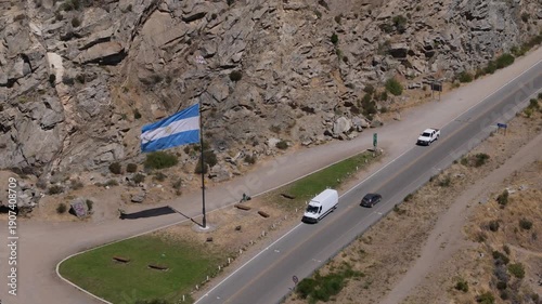 Argentine flag waving proudly over a scenic mountain road in San Martin de los Andes, Neuquen, Patagonia, representing national pride, federalism, and the spirit of the Argentine Republic.