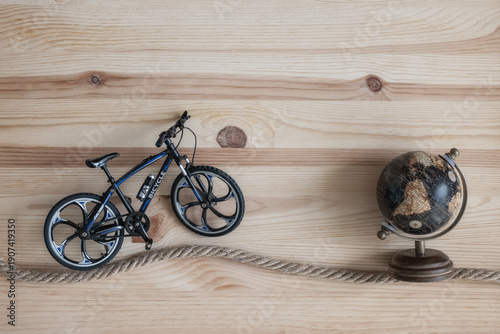 A toy bicycle, very similar to the real one, on a wooden board background. An imaginary bicycle trip.