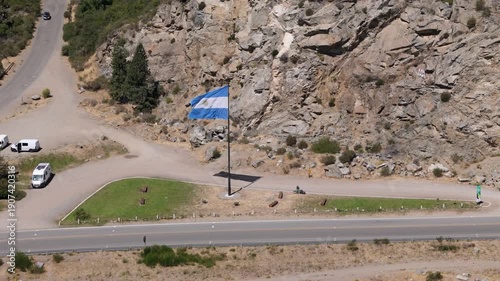 Argentine flag waving proudly over a scenic mountain road in San Martin de los Andes, Neuquen, Patagonia, representing national pride, federalism, and the spirit of the Argentine Republic.