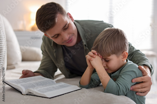 фотографія Father and his son with Bible praying at home