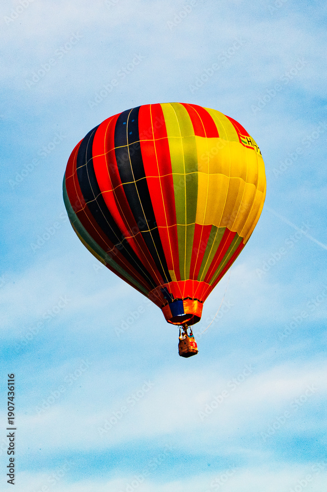 Naklejka premium Striped hot air balloon in blue sky