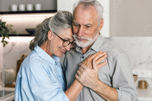 Bild auf Leinwand Senior couple smiles and embraces in their cozy home during the weekend