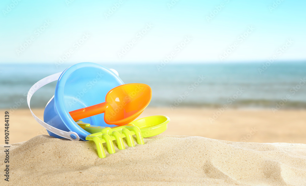 Obraz premium Bright plastic beach toys on sand near sea, banner design. Summer time