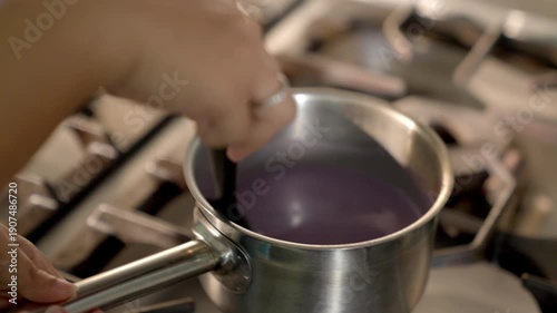 Close-up of Hand Stirring Savory Dark Wine Sauce in a Stainless Steel Saucepan