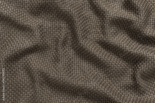 Detailed texture of taupe brown woven fabric background. Top view of neutral dark beige colored thick throw blanket material with a basket weave pattern, softly draped to create an abstract background