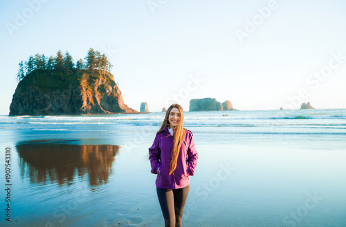 Rear view of a brunette woman on Second Beach during sunset, Olympic National Park, Washington. Outdoor lifestyle, solo travel, peaceful nature and coastal adventure concept.