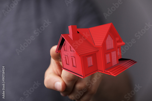A hand holding a red 3D hou...