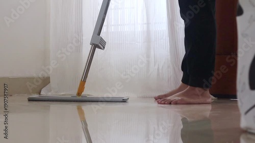 A woman mopping the floor of the house. Clean and shiny house floors.