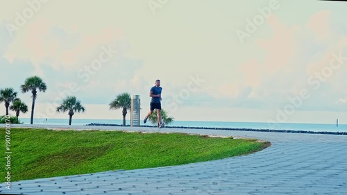 Sportsman jogger running or jogging. Man in sports suit training jogging. Running man, slow motion footage. Morning sport workout jogger run in Miami. The jogger run at sport training