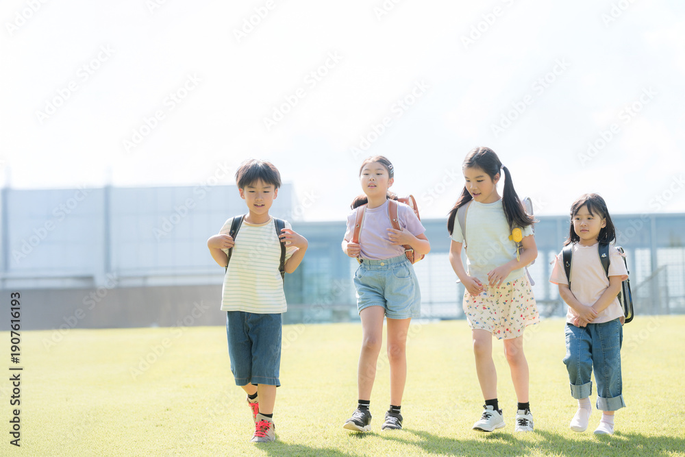 Obraz premium 学校から下校する小学生の全身 登校班で家や学童に帰る複数(3人)の子どもたち