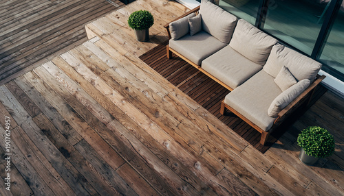Brown wooden deck with a neutral outdoor sofa set and green plants. Modern patio design for luxury backyard living and home exterior styling.
