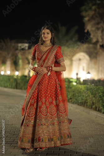 Young Indian Woman Wearing Traditional Red Bridal Lehenga at Night Outdoors