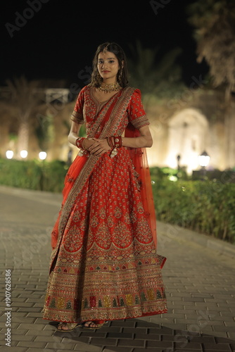 Young Indian Woman Wearing Traditional Red Bridal Lehenga at Night Outdoors