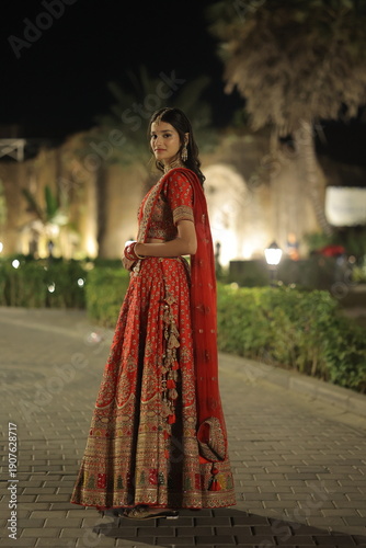 Young Indian Woman Wearing Traditional Red Bridal Lehenga at Night Outdoors