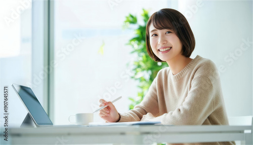 デスクでペンとタブレットを持ちこちらを見て微笑む女性 Free Download デスクでペンとタブレットを持ちこちらを見て微笑む女性 - GFXLoad