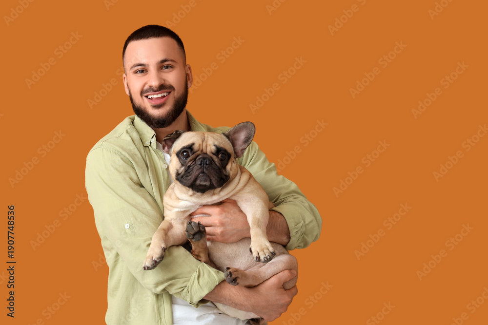 © Pixel-Shot - Handsome young happy man with cute French bulldog on yellow background