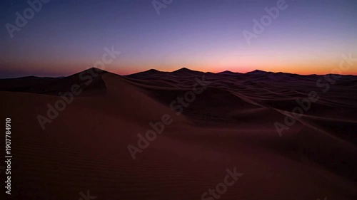 Timelapse of sunset over desert sand dunes with dramatic clouds