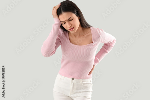 Obraz na plátně Young woman suffering from headache on light background