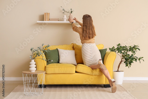 Young woman putting vase wi...
