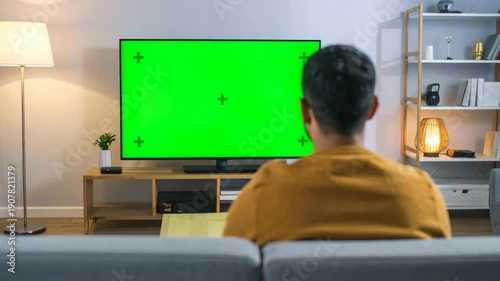 Wallpaper Mural Man sitting on sofa watching large green screen television in living room Torontodigital.ca