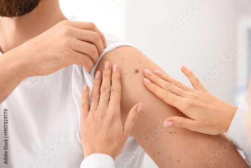 Foto Dermatologist examining moles of male patient in clinic. Closeup
