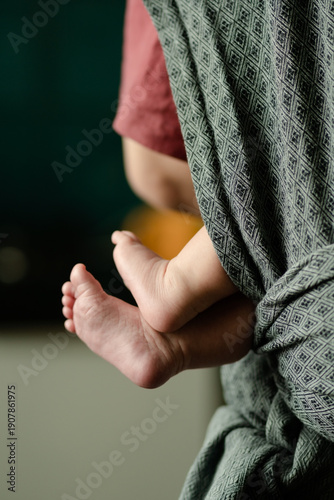 Loving father holding newborns tiny feet in baby carrier