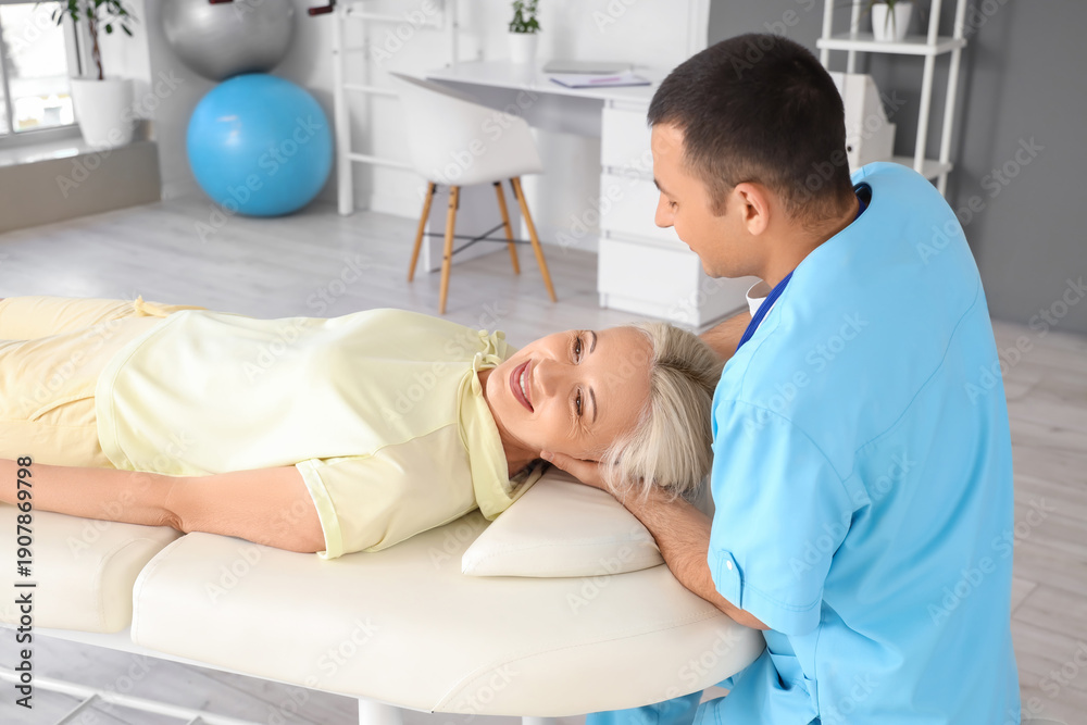 Obraz premium Male physiotherapist working with mature woman on couch in rehabilitation center