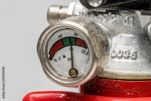 close up view of a fire extinguisher pressure gauge. the pointer indicates the pressure is within the green area, meaning the unit is properly pressurized and operational.