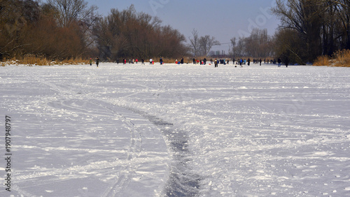 The Mures River frozen in the harsh Transylvanian winter, with people in the background enjoying themselves on the ice.