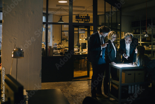 Business people and girl looking at shining tablet in office