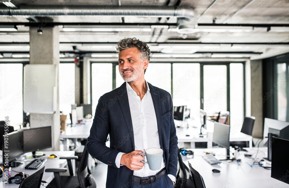 © Westend61 - Smiling mature businessman with coffee mug in office
