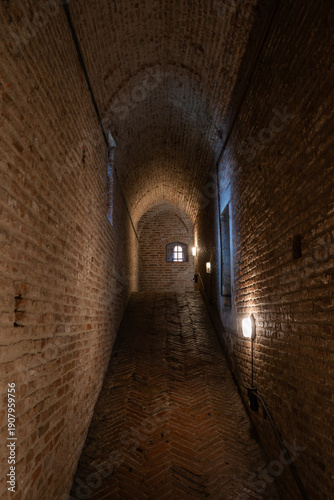 A dark, brick-walled passageway inside Castello Estense in Ferrara, evoking medieval atmosphere and historic architecture. Ferrara,Italy 03.01.2026
