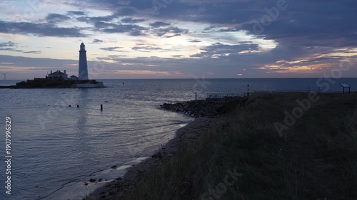 A panoramic wide shot of St Mary’s Lighthouse on its tidal island, captured from the rugged low cliffs of Whitley Bayat dawn