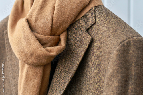 Warm wool scarf wrapped around tailored beige coat, symbolizing comfort, elegance, and slow fashion in cold season. Selective focus.