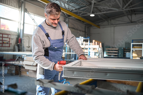 Slika na platnu Proficient worker engaged in construction of PVC doors and windows