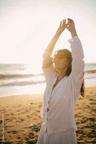 Beautiful 40 years old woman relaxing on the beach at sunset.