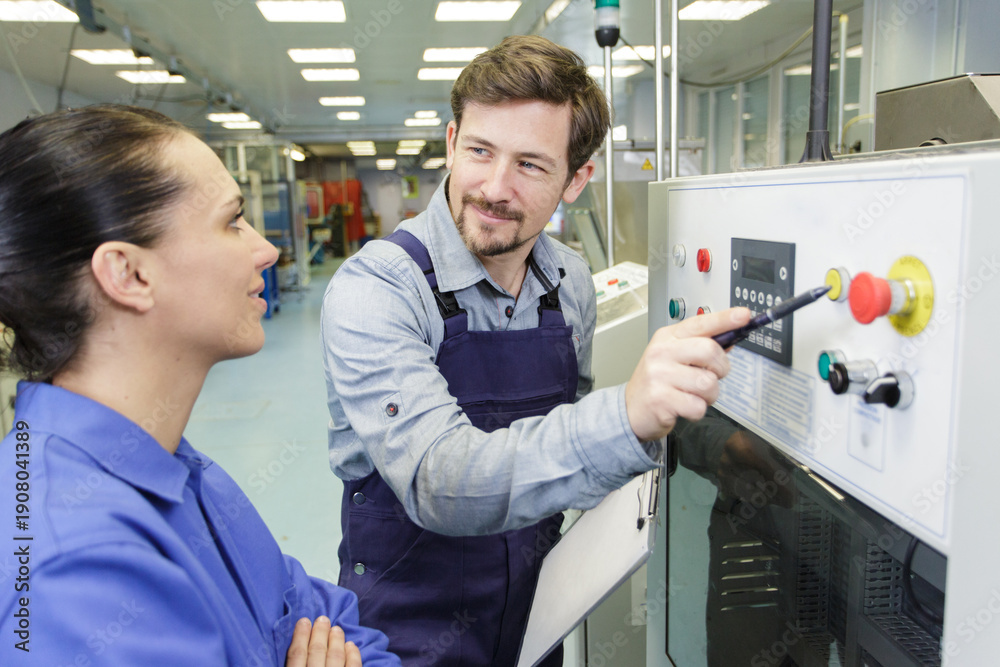 Obraz premium man and woman operating a machine in a factory